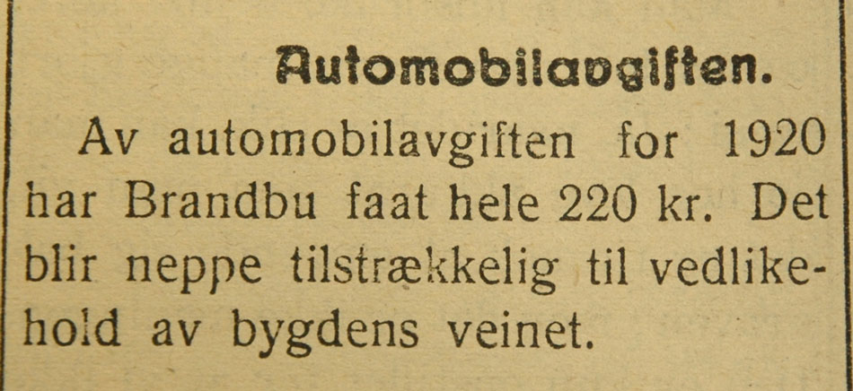 Bilde av notis i avisen Hadeland i 1921 om automobilavgift på Brandbu for 220kr. Notisen nevner at dette neppe er tilstrekkelig for Brandbus veinett