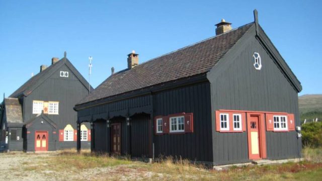 Fokstua stasjon, godshuset i forgrunnen med stasjonsbygningen bak (Fotograf: Dagmar Buen © Fylkesarkivet i Oppland). Bilde av godshuset og stasjonsbygget på Fokstua stasjon