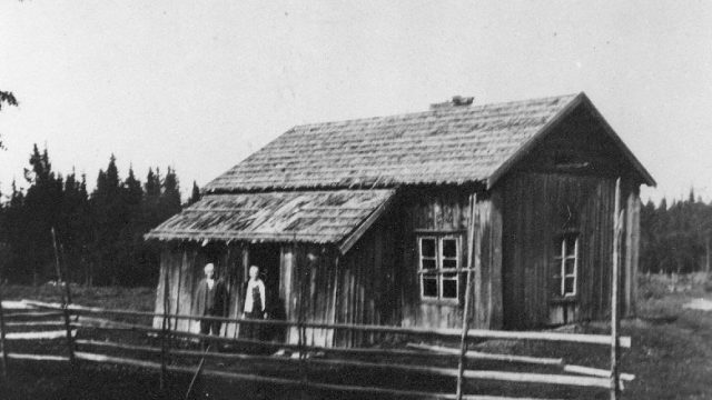 Digtimot under Berg gård, Gjøvik, ca. 1935. - På bildet ser vi August og Mathea Andreassen Digtimot. – Foto: Mjøsmuseet Hus med mann og kvinne foran