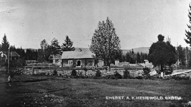 Elvsveen og Sveum, Østre Toten, 1922 - To husmannsplasser på Skreia. Foran på bildet ser vi husmannsbruket Elvsveen, og bak husmannsbruket Sveum. Bakerst til venstre er huset til mølleren i Kvernum, Johan Eneberg. Bildet er tatt i 1922. – Fotograf: A. K. Hensvold. Foto: Mjøsmuseet, R 80/013/09. Jorde med gjerder og hus i bakgrunnen