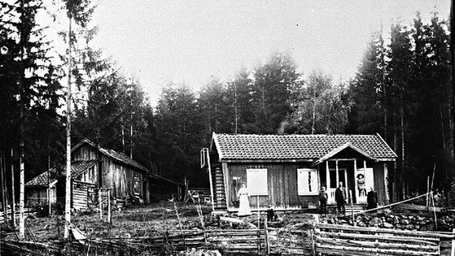 Plassen Granli under Horgen. Granli ligger nordøst for Nordtangen, Gran kommune. Husets høyre del var tidligere badstu på vestre Framstad. Tilbygget er i reisverk. Hans Jacobsen Granli (1857-1934) som bygget Granli og konen han Marte (1856-1942) flyttet inn på plassen i 1894. Hans eide huset, men ikke jorda. Han arbeidet to dager i året på Horgen søndre for leie av jorda. Bildet er fra 1909. – Fotograf: Lars Bleken, Foto: Randsfjordmuseene AS Hus med gardsplass, familie foran og andre bygninger til siden