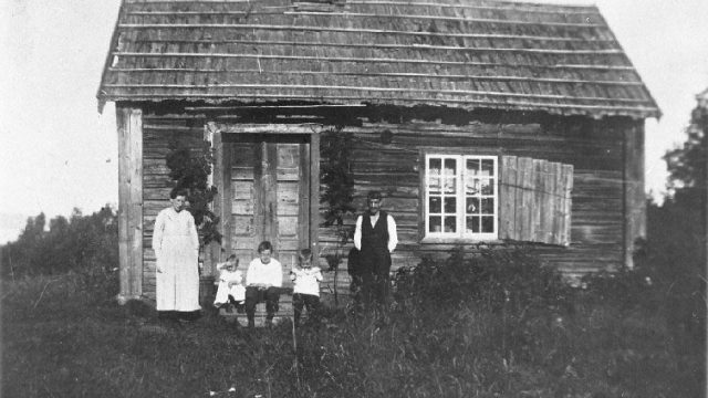 Hågåstua, Vestre Toten - Plass under Hjelpestein øvre. Bildet er tatt i 1920, og viser Klara, Else, Marry, Arman og Alek Børresen, som leide dette ei tid. – Fotograf: Ukjent. Foto: Mjøsmuseet / R 98/008/08. Familie med tre barn foran hus